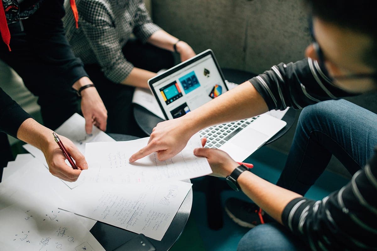 A team collaborating around a laptop and working through a business process